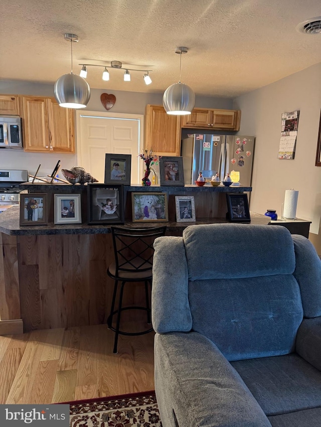 71 Shultz Way, Moorefield, WV 26836 - kitchen featuring stainless steel appliances, open floor plan, a kitchen bar, hanging light fixtures, and a textured ceiling