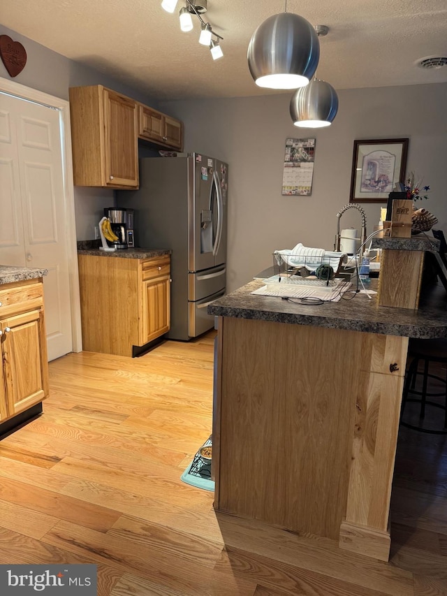 71 Shultz Way, Moorefield, WV 26836 - kitchen featuring light wood-type flooring, stainless steel fridge, dark countertops, a kitchen bar, and decorative light fixtures