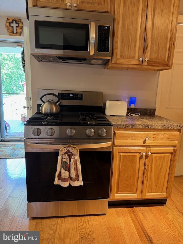 71 Shultz Way, Moorefield, WV 26836 - kitchen with appliances with stainless steel finishes, light wood-type flooring, dark countertops, and brown cabinets