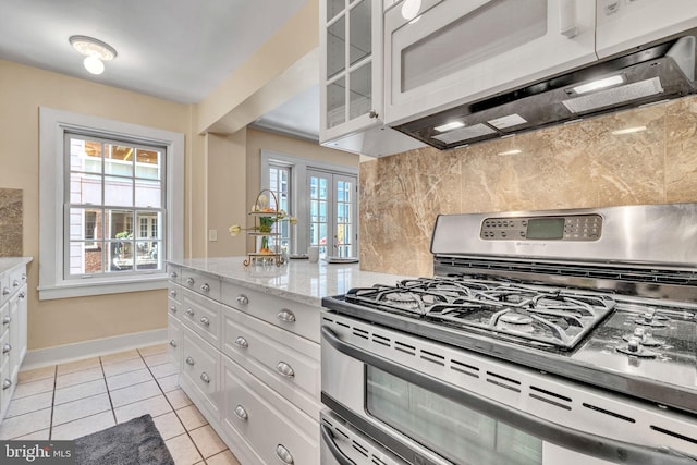 1026 16th St NW Unit 505, Washington, DC 20036 - kitchen featuring gas range, white microwave, french doors, backsplash, and white cabinetry