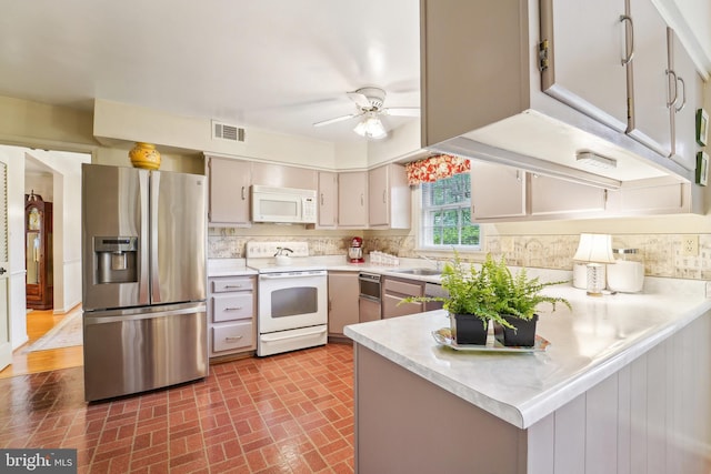 15320 Durant St, Silver Spring, MD 20905 - kitchen featuring white appliances, a peninsula, brick patterned flooring, light countertops, and tasteful backsplash