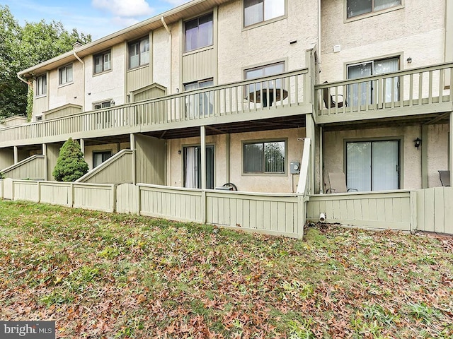 rear view of house featuring stucco siding and a balcony