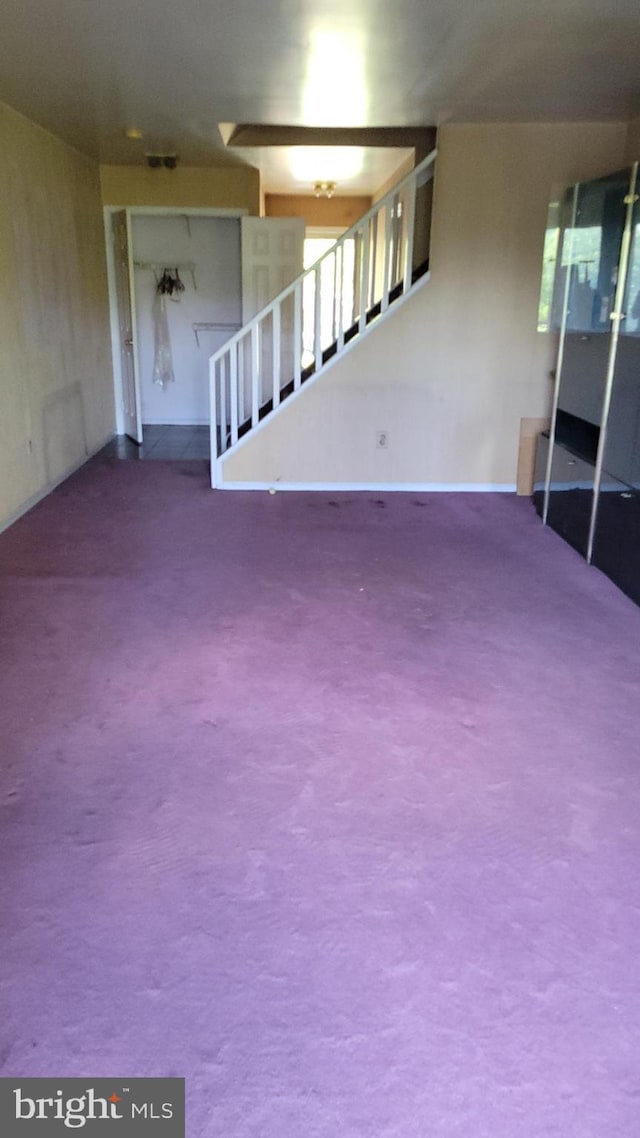 below grade area featuring stairs and carpet flooring