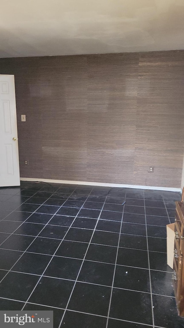 spare room featuring dark tile patterned floors and baseboards