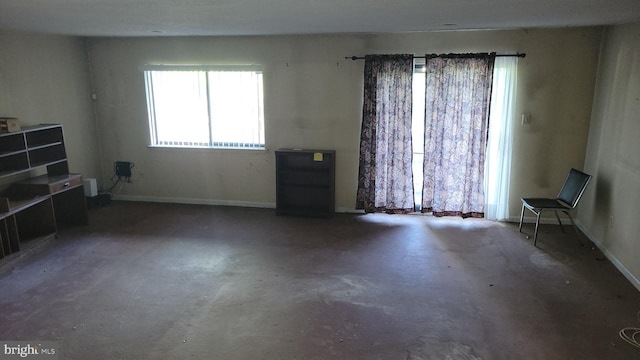 unfurnished living room with concrete floors and baseboards