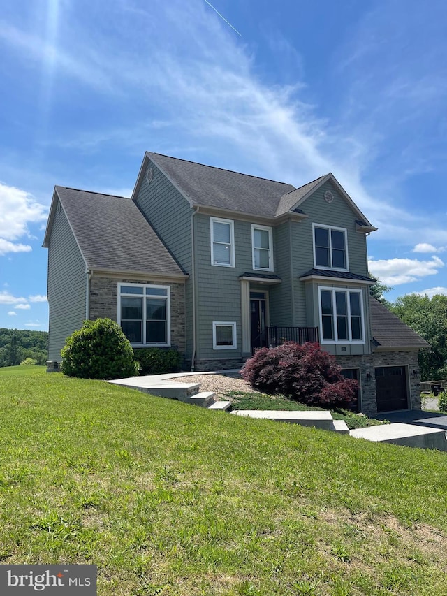 view of front of property with stone siding, a front lawn, driveway, and roof with shingles