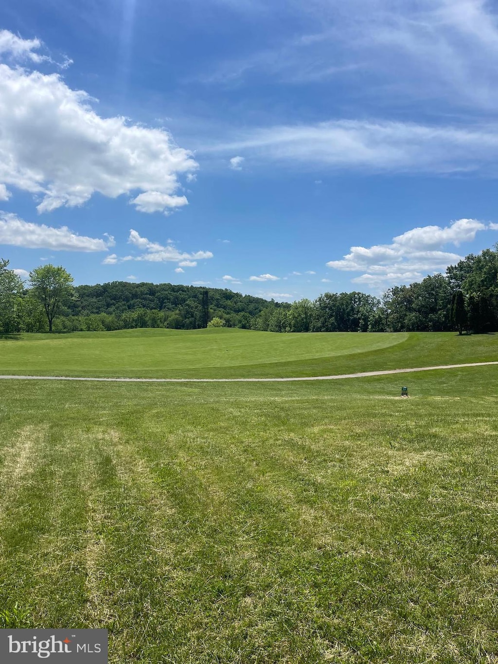 view of home's community with view of golf course, a lawn, and view of wooded area