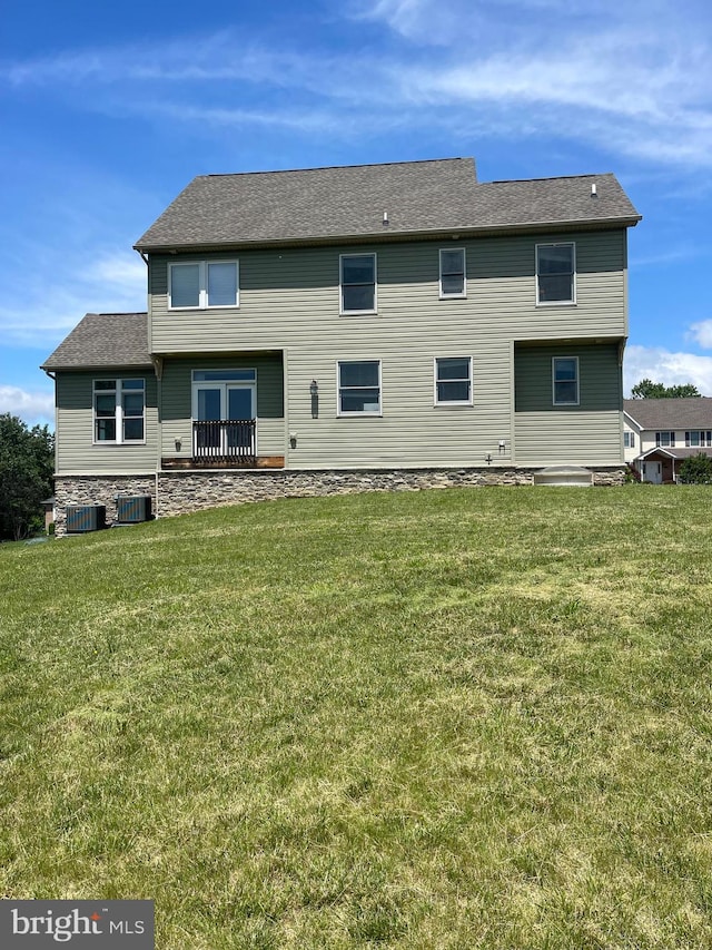 rear view of property featuring central AC unit and a yard