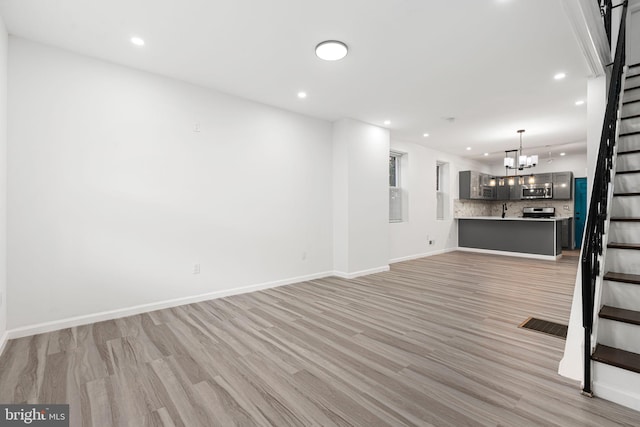 5514 Broomall St, Philadelphia, PA 19143 - unfurnished living room with stairs, light wood-style flooring, a chandelier, recessed lighting, and baseboards