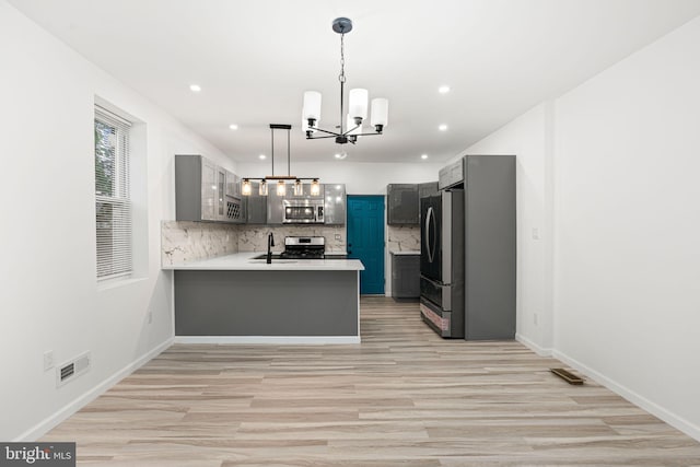 5514 Broomall St, Philadelphia, PA 19143 - kitchen featuring stainless steel appliances, a chandelier, backsplash, light wood-type flooring, and a sink