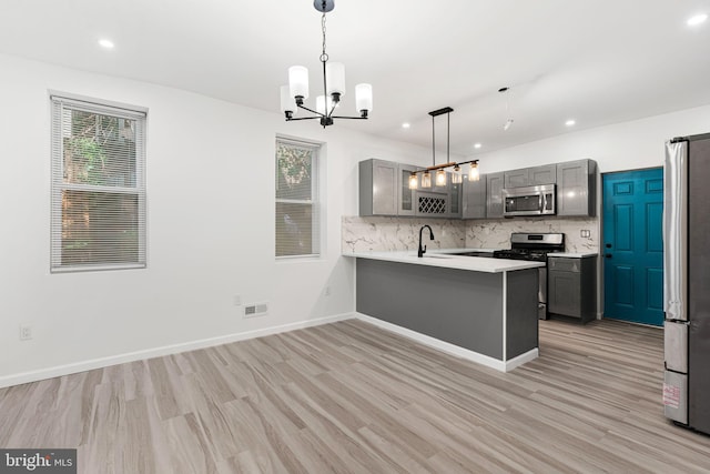 5514 Broomall St, Philadelphia, PA 19143 - kitchen with appliances with stainless steel finishes, gray cabinetry, a chandelier, light wood-type flooring, and backsplash