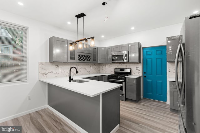 5514 Broomall St, Philadelphia, PA 19143 - kitchen featuring stainless steel appliances, a sink, gray cabinets, a peninsula, and decorative backsplash