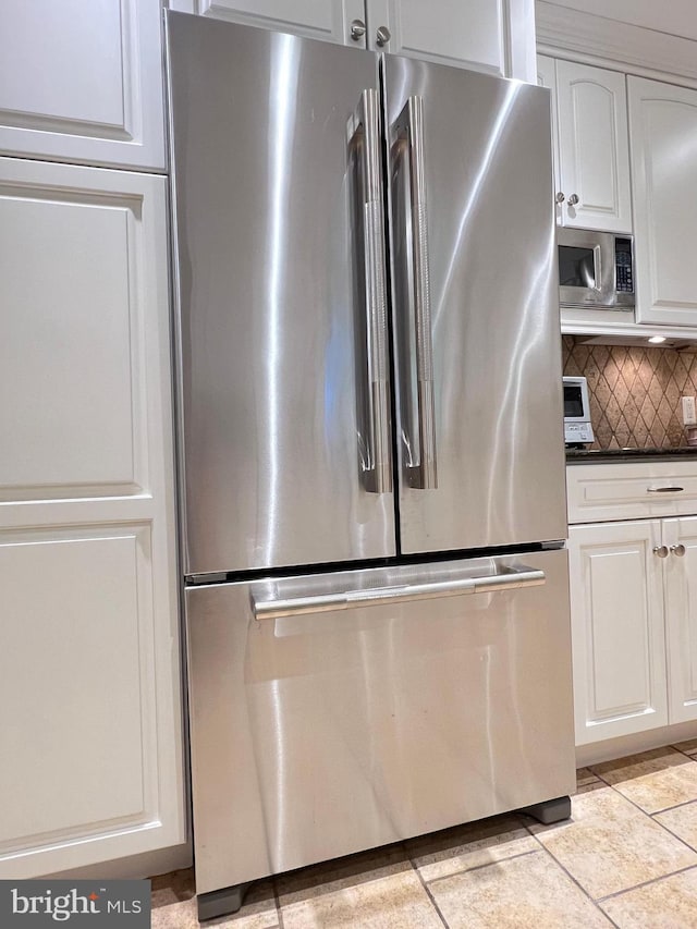 1027 Hart Rd, Baltimore, MD 21286 - kitchen featuring appliances with stainless steel finishes, dark countertops, decorative backsplash, white cabinets, and light tile patterned floors