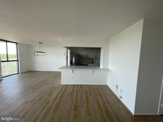 unfurnished living room featuring wood finished floors, a wall of windows, and baseboards