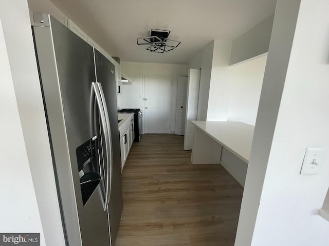 kitchen with stainless steel refrigerator with ice dispenser, light wood finished floors, white cabinets, and light countertops