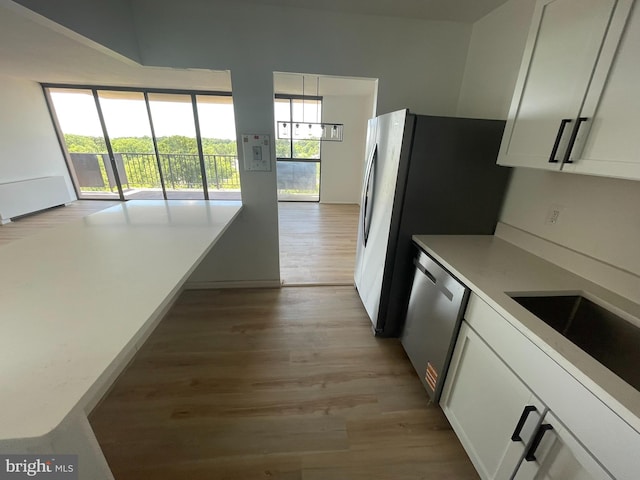 kitchen featuring light wood-style flooring, dishwasher, white cabinetry, light countertops, and a sink