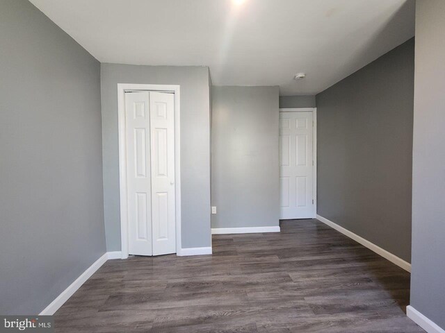 713 N Payson St, Baltimore, MD 21217 - unfurnished bedroom featuring baseboards, a closet, and dark wood-style flooring