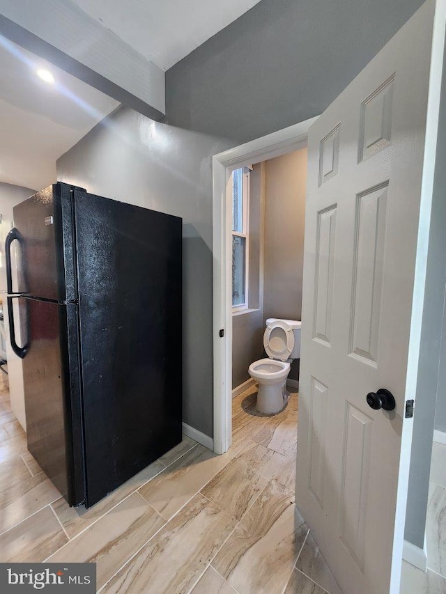 713 N Payson St, Baltimore, MD 21217 - bathroom with toilet, marble look tile flooring, and baseboards