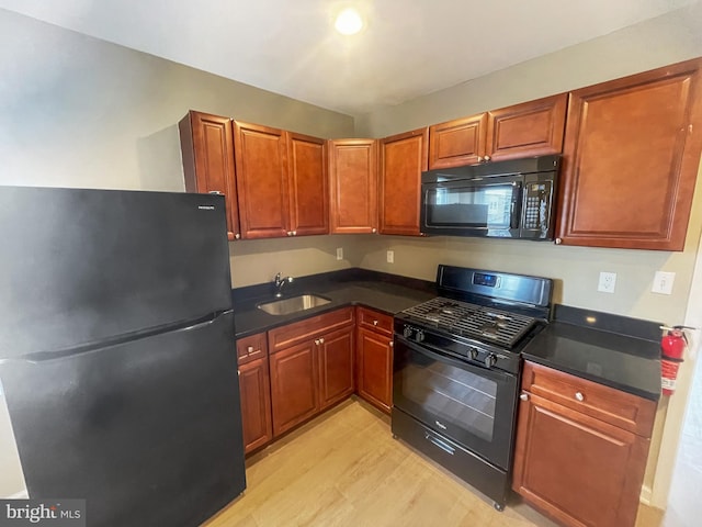 978 N 45th St, Philadelphia, PA 19104 - kitchen with black appliances, a sink, light wood finished floors, dark countertops, and brown cabinetry