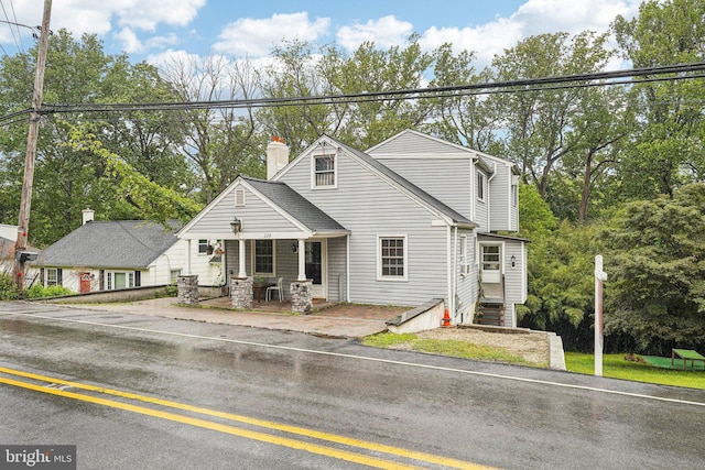 228 Balligomingo Rd, Conshohocken, PA 19428 - view of front of property with covered porch, a chimney, and view of wooded area