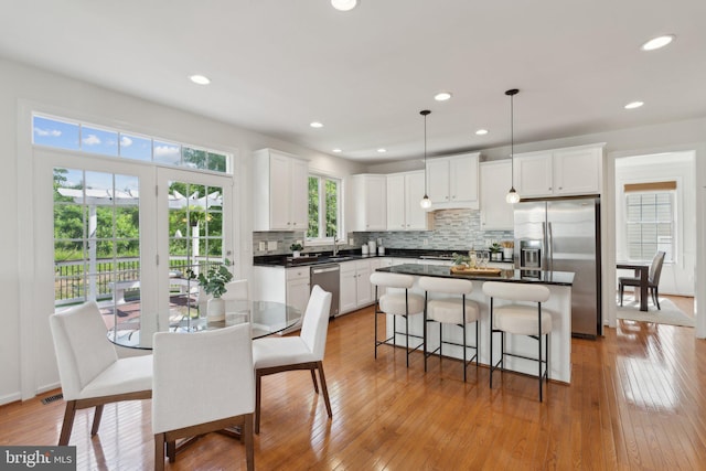 42322 Rising Moon Pl, Brambleton, VA 20148 - kitchen featuring appliances with stainless steel finishes, white cabinetry, tasteful backsplash, a kitchen bar, and recessed lighting