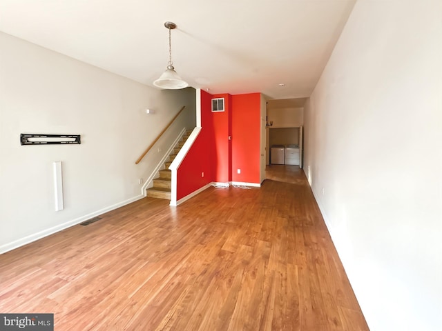 2426 Jefferson St, Baltimore, MD 21205 - unfurnished living room with stairs, washer and clothes dryer, light wood-style floors, and baseboards