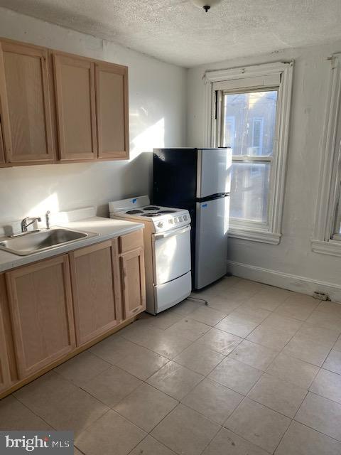 2617 N Bancroft St, Philadelphia, PA 19132 - kitchen with white electric range, a sink, a textured ceiling, light brown cabinets, and light countertops