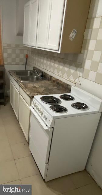 2617 N Bancroft St, Philadelphia, PA 19132 - kitchen featuring white electric range oven, a sink, light tile patterned floors, white cabinets, and backsplash