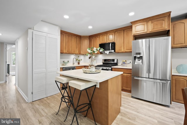 5050 7th Rd S Unit 201, Arlington, VA 22204 - kitchen featuring stainless steel appliances, light countertops, light wood-style flooring, a kitchen island, and a kitchen bar