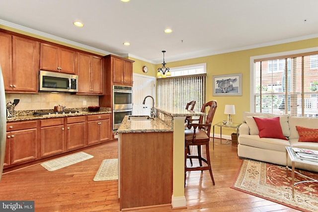 120 Fortnightly Blvd, Herndon, VA 20170 - kitchen featuring stainless steel appliances, a sink, a breakfast bar area, ornamental molding, and light wood-type flooring