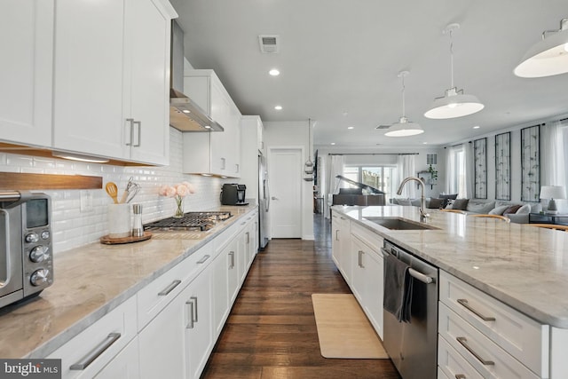 kitchen featuring a sink, stainless steel appliances, open floor plan, white cabinetry, and dark wood finished floors