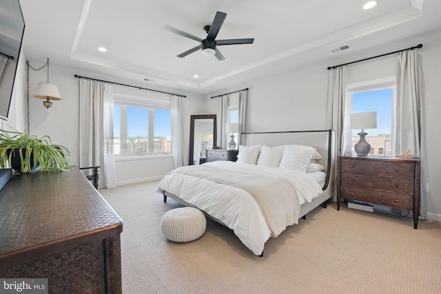 bedroom with a tray ceiling, light carpet, recessed lighting, and baseboards