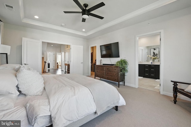 bedroom featuring a raised ceiling, recessed lighting, baseboards, ensuite bath, and light colored carpet