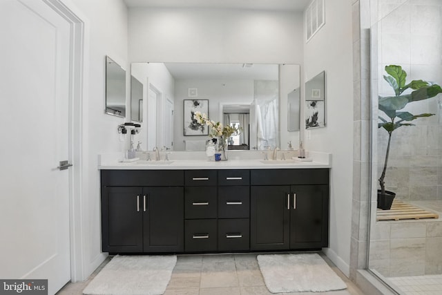 bathroom featuring tiled shower, double vanity, baseboards, and tile patterned flooring