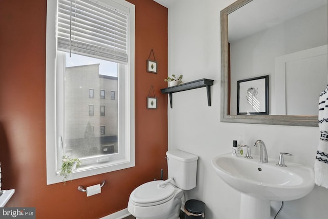 bathroom with toilet, a sink, and baseboards