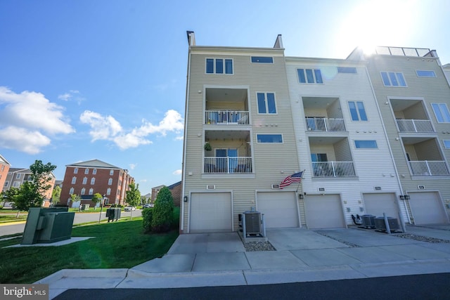view of apartment building / complex featuring an attached garage, driveway, and cooling unit