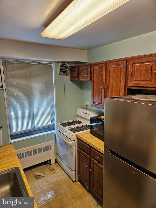 5410 Connecticut Ave NW Unit 112, Washington, DC 20015 - kitchen with freestanding refrigerator, white range with gas stovetop, radiator heating unit, and wooden counters