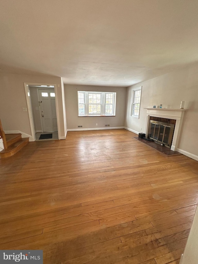 409 Whitfield Rd, Baltimore, MD 21228 - unfurnished living room with light wood-type flooring, baseboards, stairs, and a fireplace