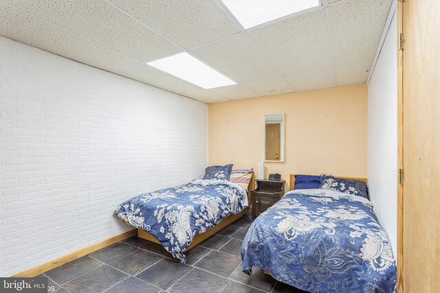 2400 Willow Glen Dr, Baltimore, MD 21209 - tiled bedroom featuring a drop ceiling, brick wall, and baseboards