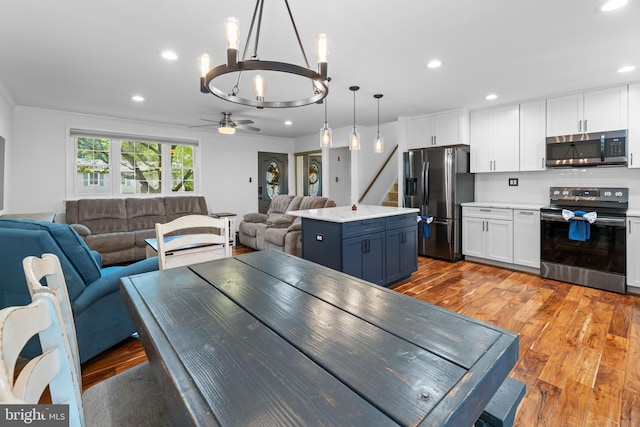 9761 Turnbuckle Dr, Burke, VA 22015 - dining room featuring a chandelier, light wood-style flooring, recessed lighting, a ceiling fan, and stairs