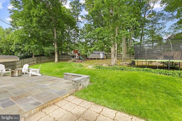 9761 Turnbuckle Dr, Burke, VA 22015 - view of yard featuring a trampoline, a playground, a patio, and a fire pit