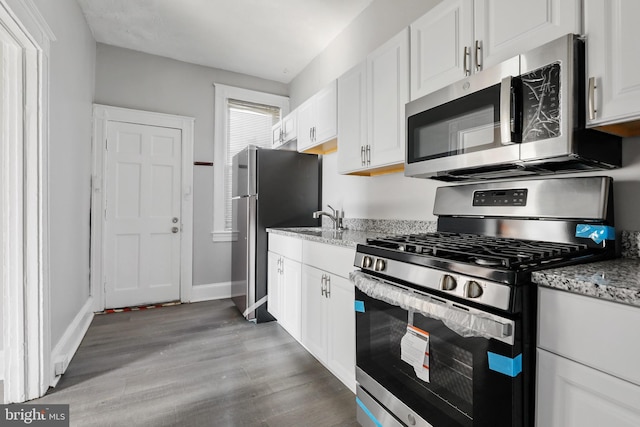 3532 Lucille Ave, Baltimore, MD 21215 - kitchen with appliances with stainless steel finishes, light wood-style flooring, white cabinets, and light stone counters