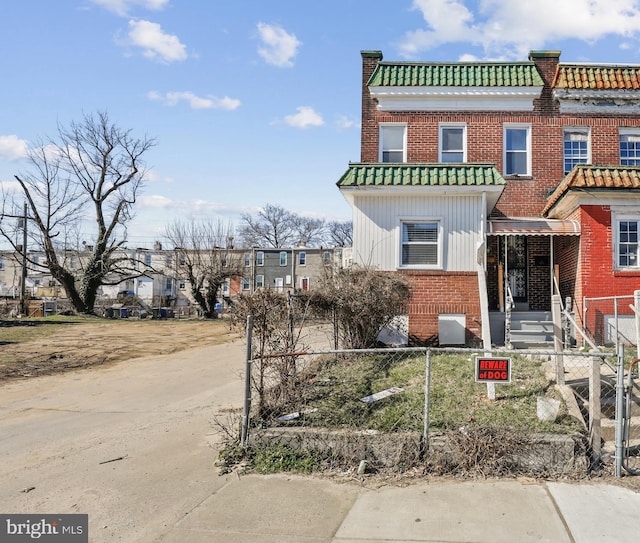 3532 Lucille Ave, Baltimore, MD 21215 - view of front of house with brick siding, a fenced front yard, and a tiled roof