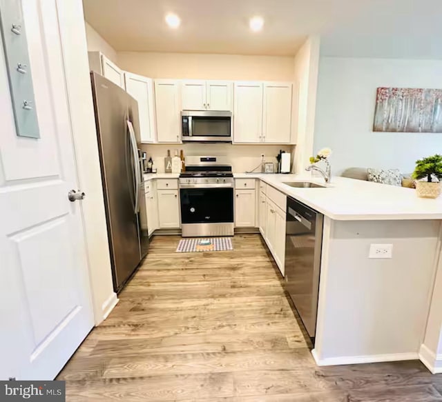 166 Sickler Ct, Sicklerville, NJ 08081 - kitchen with appliances with stainless steel finishes, a sink, light wood-style floors, a peninsula, and light countertops