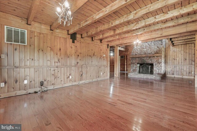 21142 Westerly Rd, Poolesville, MD 20837 - unfurnished living room featuring wood-type flooring, a chandelier, wood walls, a stone fireplace, and a wooden ceiling with exposed beams