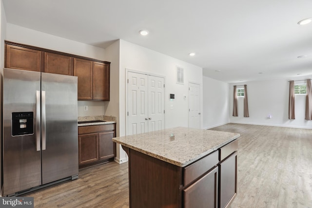 11041 Lee St, King George, VA 22485 - kitchen featuring stainless steel refrigerator with ice dispenser, wood finished floors, a kitchen island, light stone counters, and baseboards