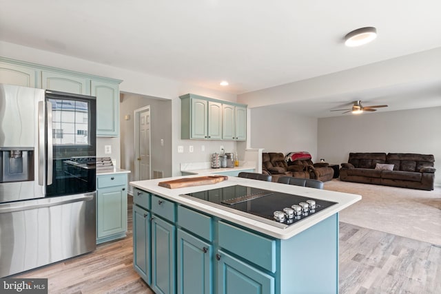 9235 Stephanie St, Manassas Park, VA 20111 - kitchen featuring stainless steel fridge, black electric cooktop, light wood-type flooring, a kitchen island, and recessed lighting