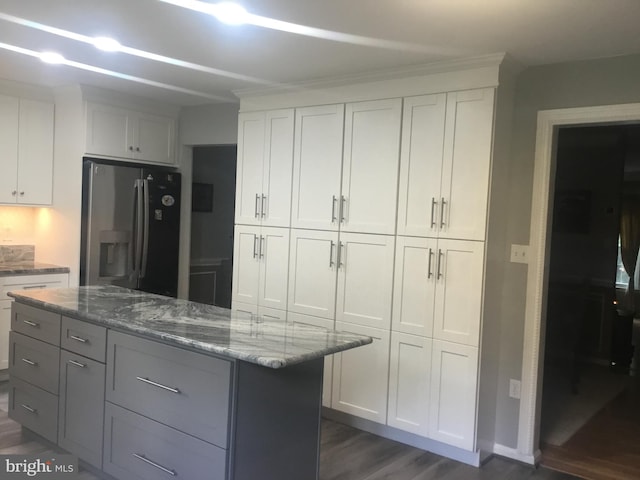 7709 Gromwell Ct, Springfield, VA 22152 - kitchen featuring stainless steel fridge, dark wood-style floors, light stone countertops, a center island, and white cabinets