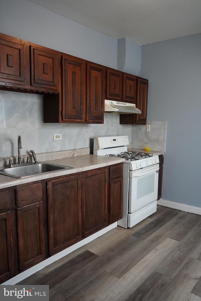 1506 Centre Ave, Reading, PA 19601 - kitchen featuring white range with gas stovetop, under cabinet range hood, a sink, dark wood finished floors, and backsplash