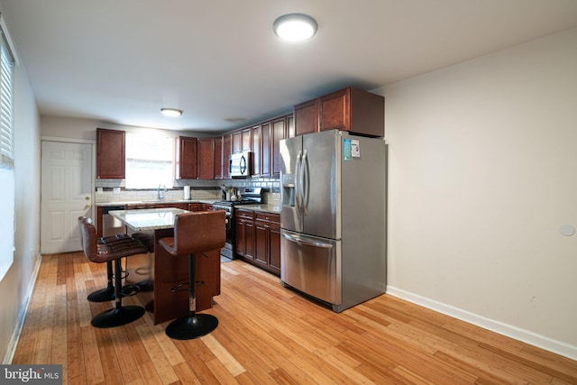 1531 Swain St, Philadelphia, PA 19130 - kitchen featuring stainless steel appliances, a kitchen breakfast bar, light wood-style floors, decorative backsplash, and a kitchen island
